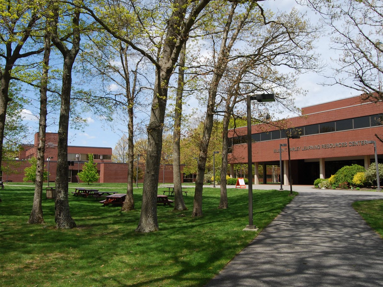Bristol Community College's Fall River campus, with the Eileen T. Farley Learning Resources Center behind a lawn of trees and picnic tables