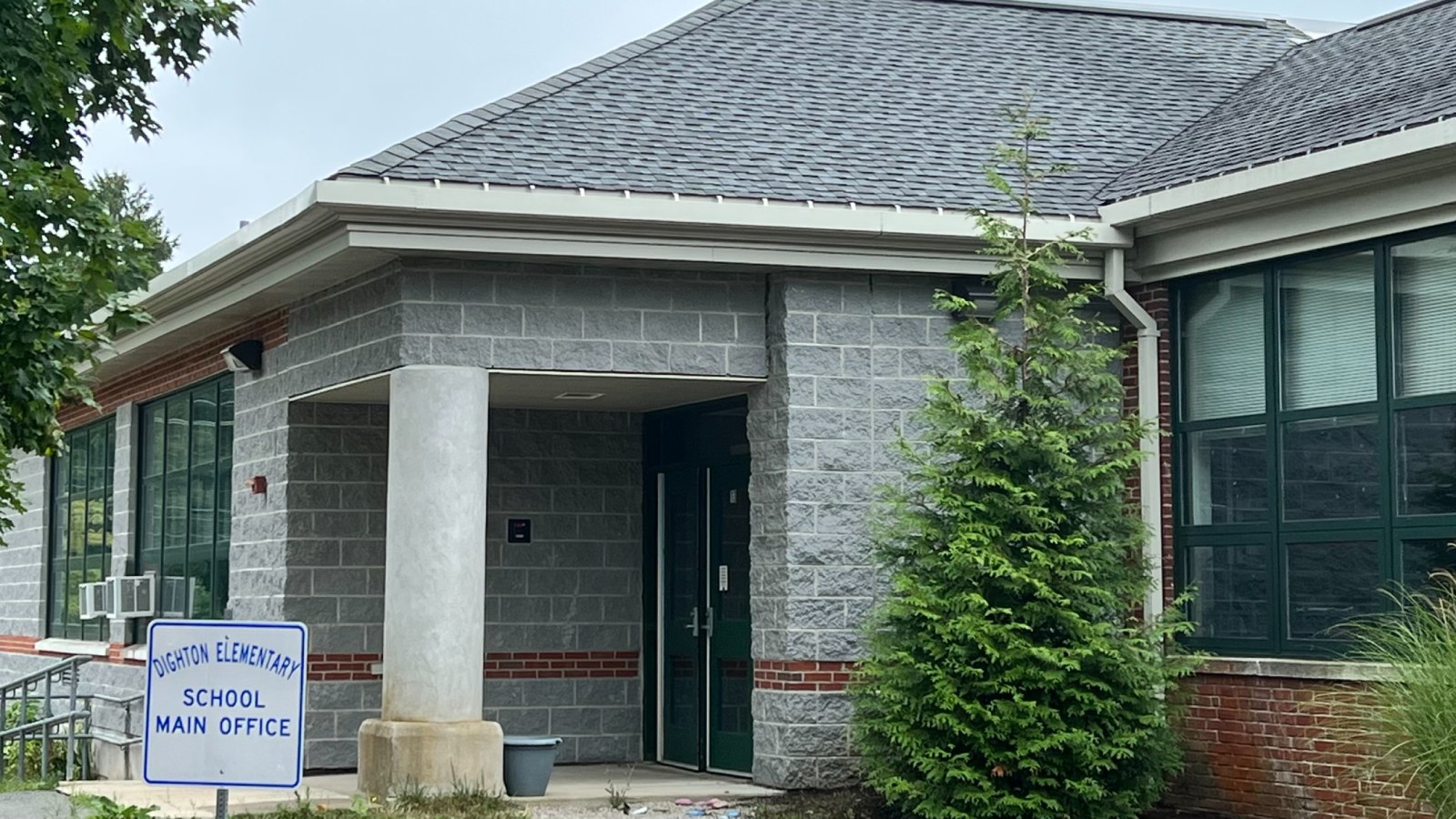 The main office entrance of Dighton Elementary School, a gray block and red brick building with a sign reading Dighton Elementary School Main Office