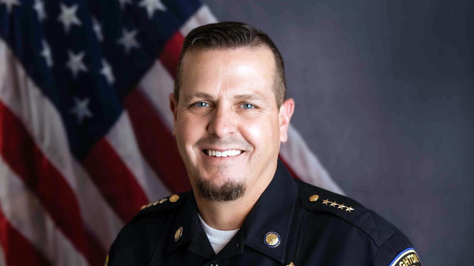 Dighton Police Chief George L. Nichols Jr. in uniform in front of an American flag