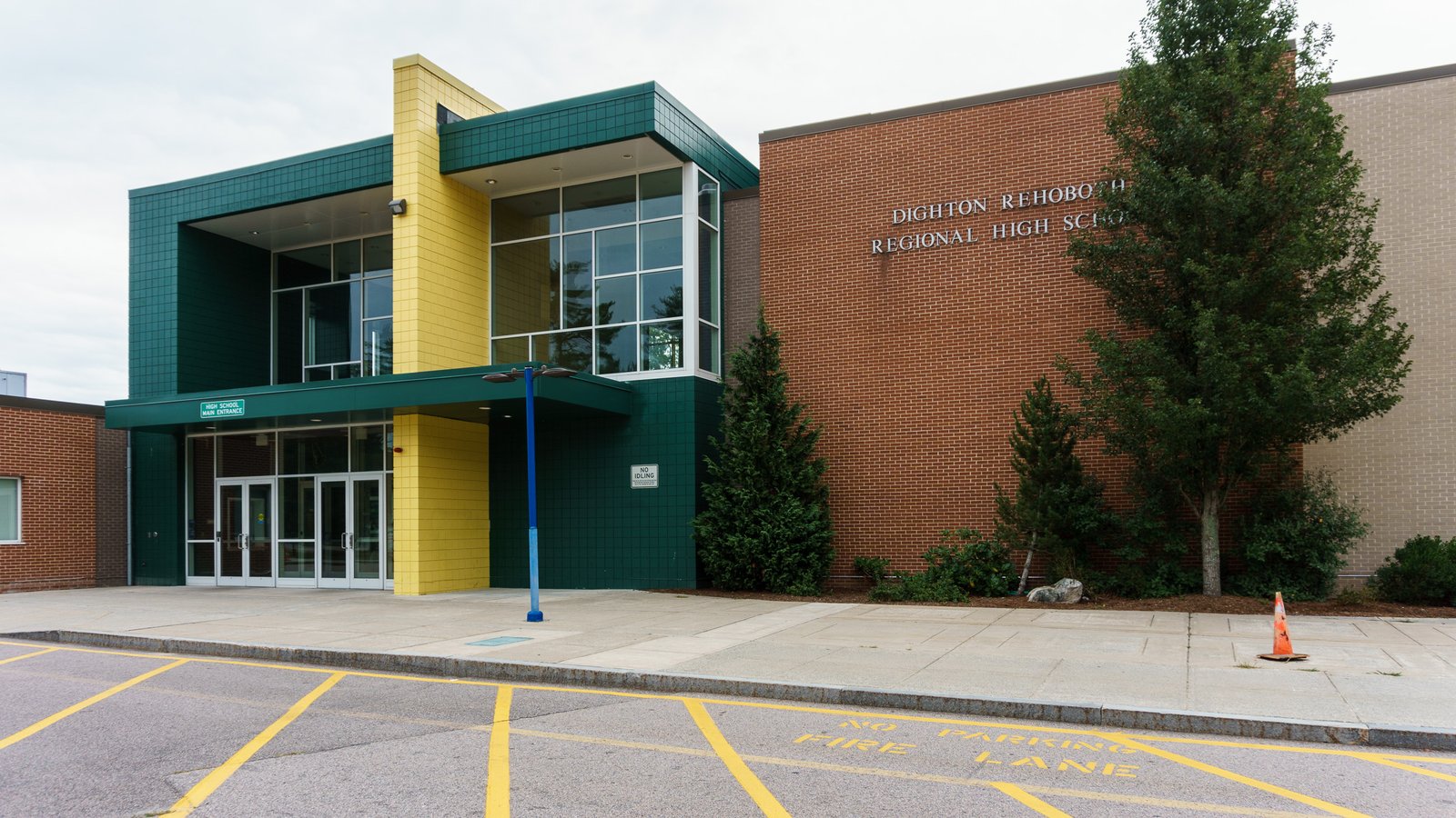 Main entrance to Dighton-Rehoboth Regional High School, a green and yellow glass entryway beside a brick wall with the school's name in metal letters