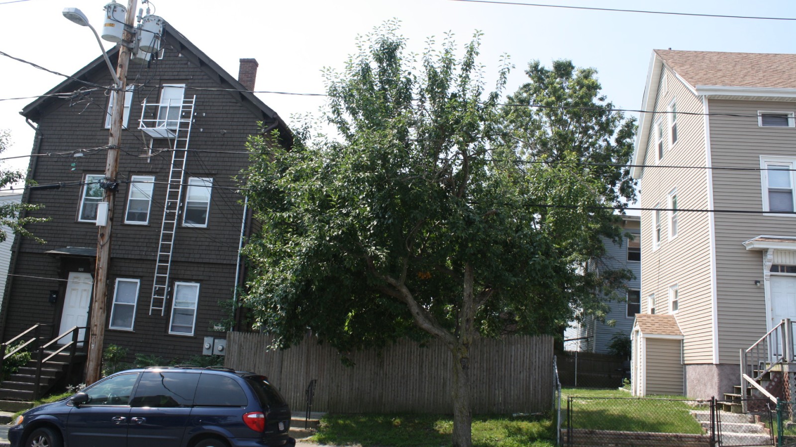 Multi-family houses along Peckham Street in Fall River, with a minivan parked at the curb