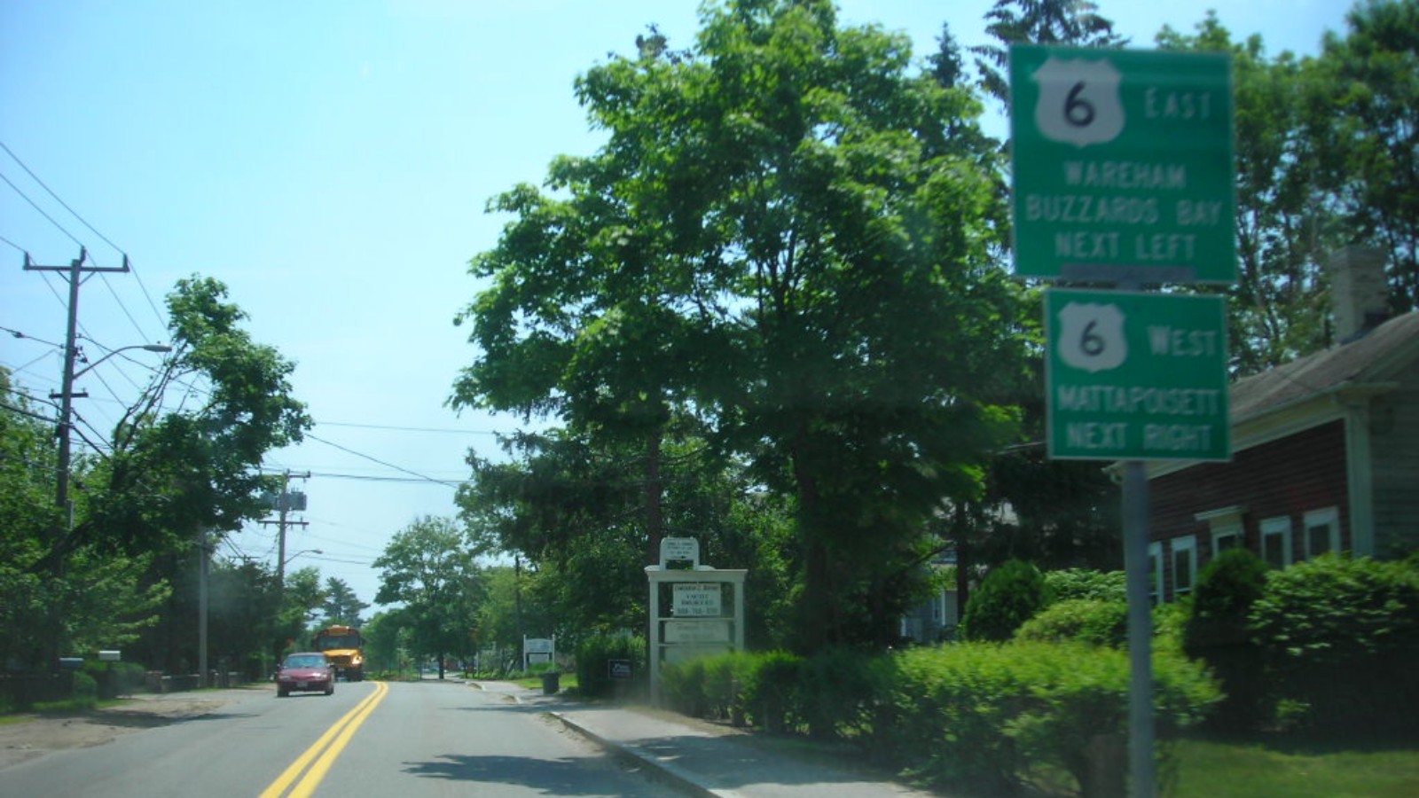 Green guide signs on Route 105 southbound in Marion reading Route 6 East, Wareham, Buzzards Bay, next left, and Route 6 West, Mattapoisett, next right, beside a two-lane road lined with trees