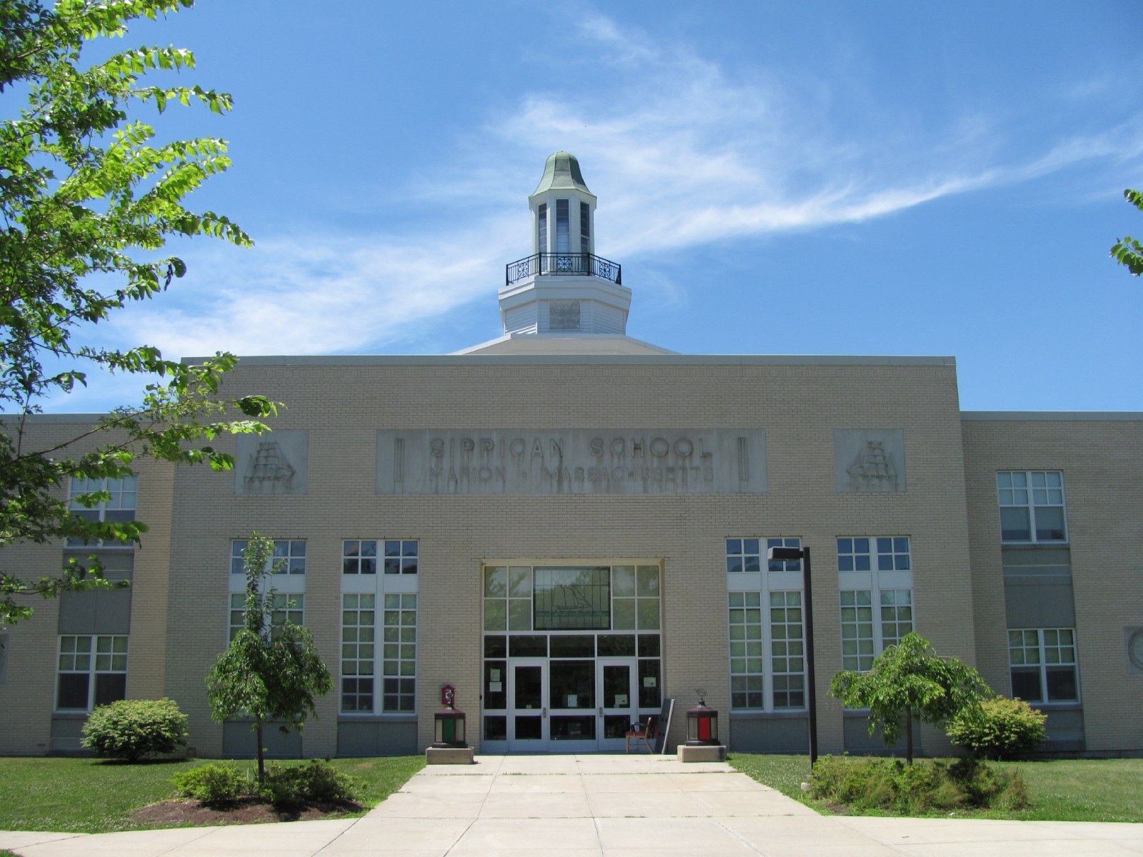 Sippican School in Marion, a long tan brick building with a white cupola above the front entrance and the school's name carved over the doors