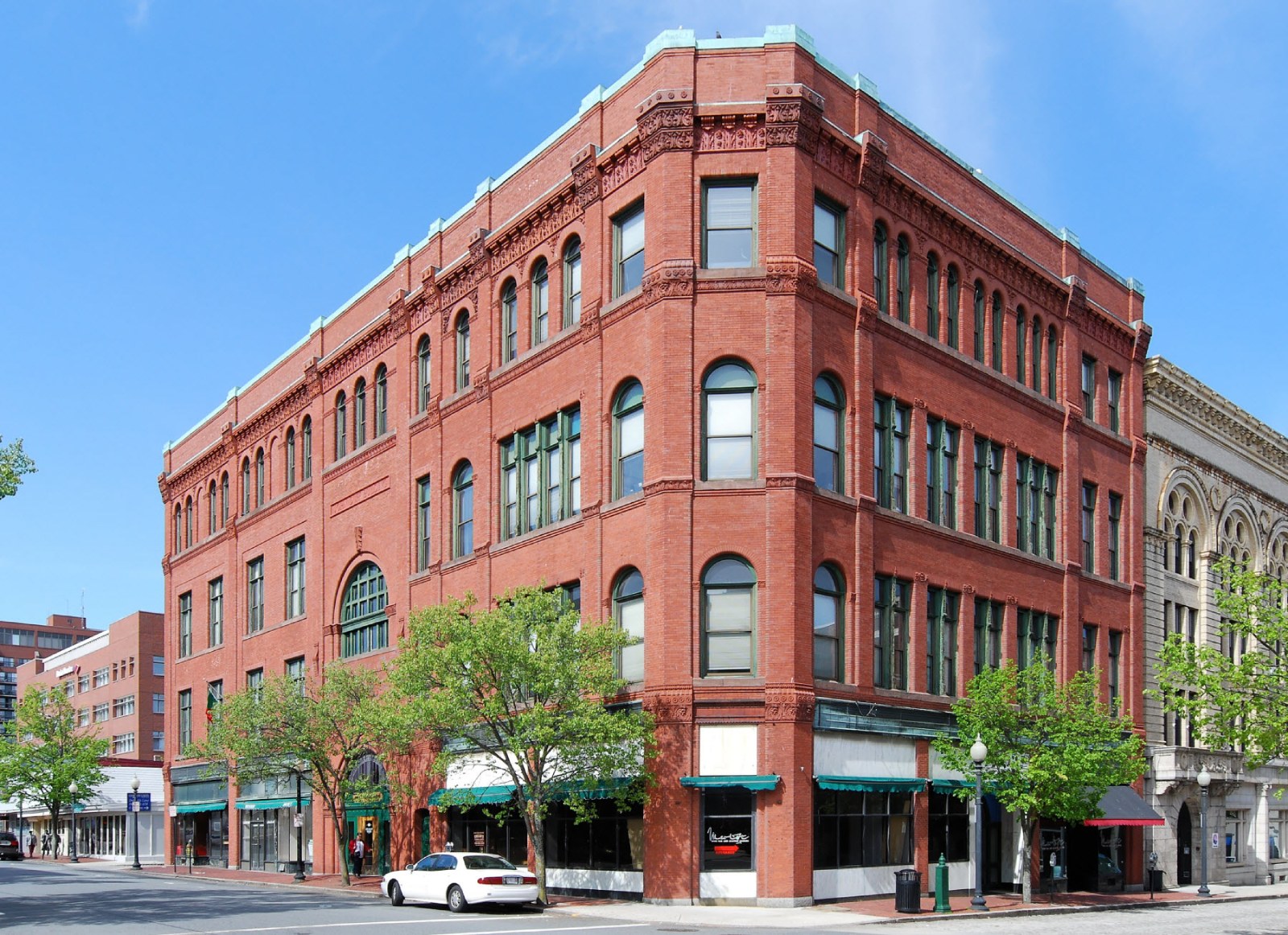 The Duff Building, a red brick block with arched windows and green awnings, on a corner in downtown New Bedford