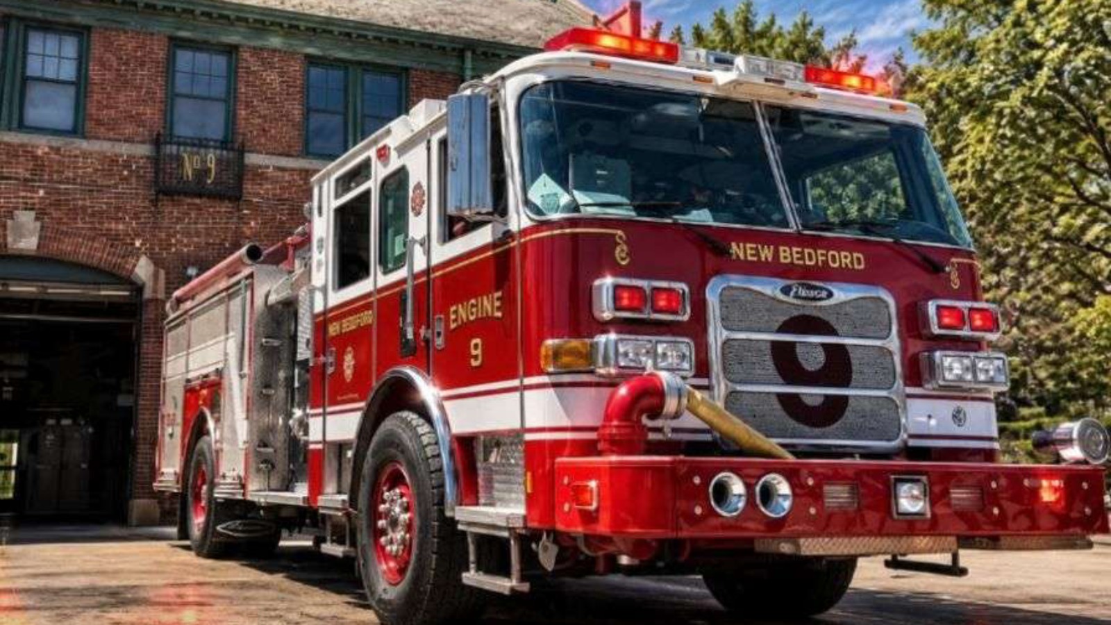 New Bedford Fire Department Engine 9, a red and white pumper with a large 9 on its grille, parked in front of a brick firehouse marked No. 9