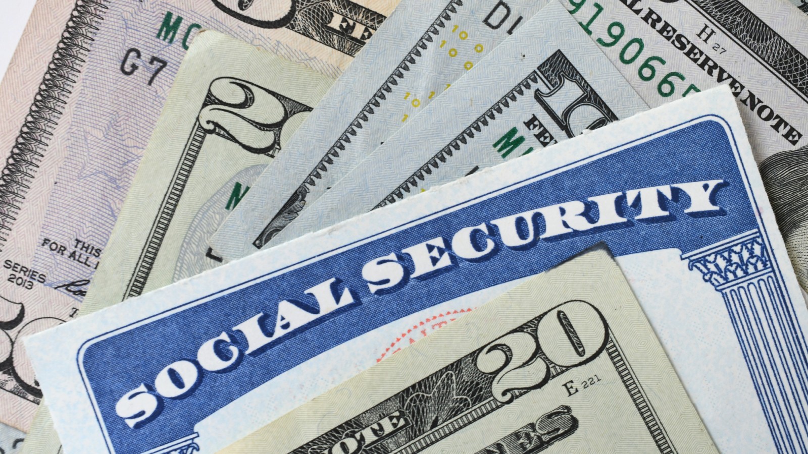 A blank Social Security card resting on fanned U.S. bills