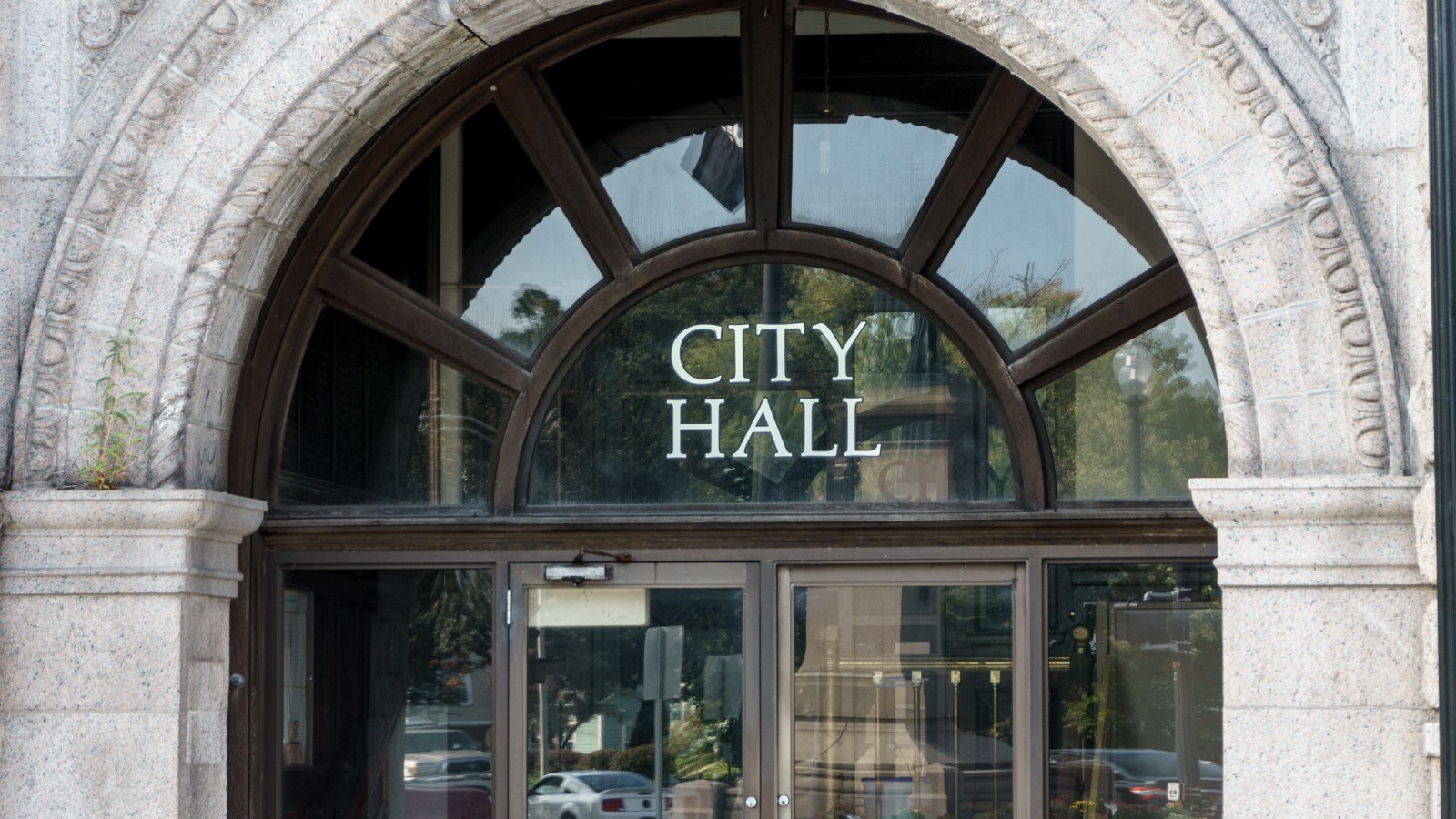 The granite entrance arch of Taunton City Hall with CITY HALL lettered on the fanlight window above glass double doors