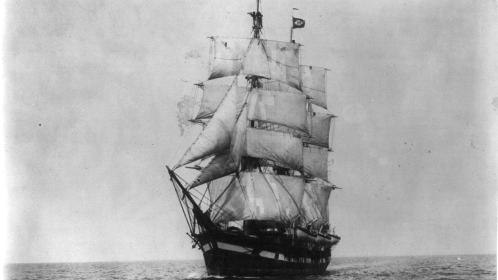 The whaling bark Wanderer sailing toward the camera under full sail on open water, in a 1922 black and white photograph
