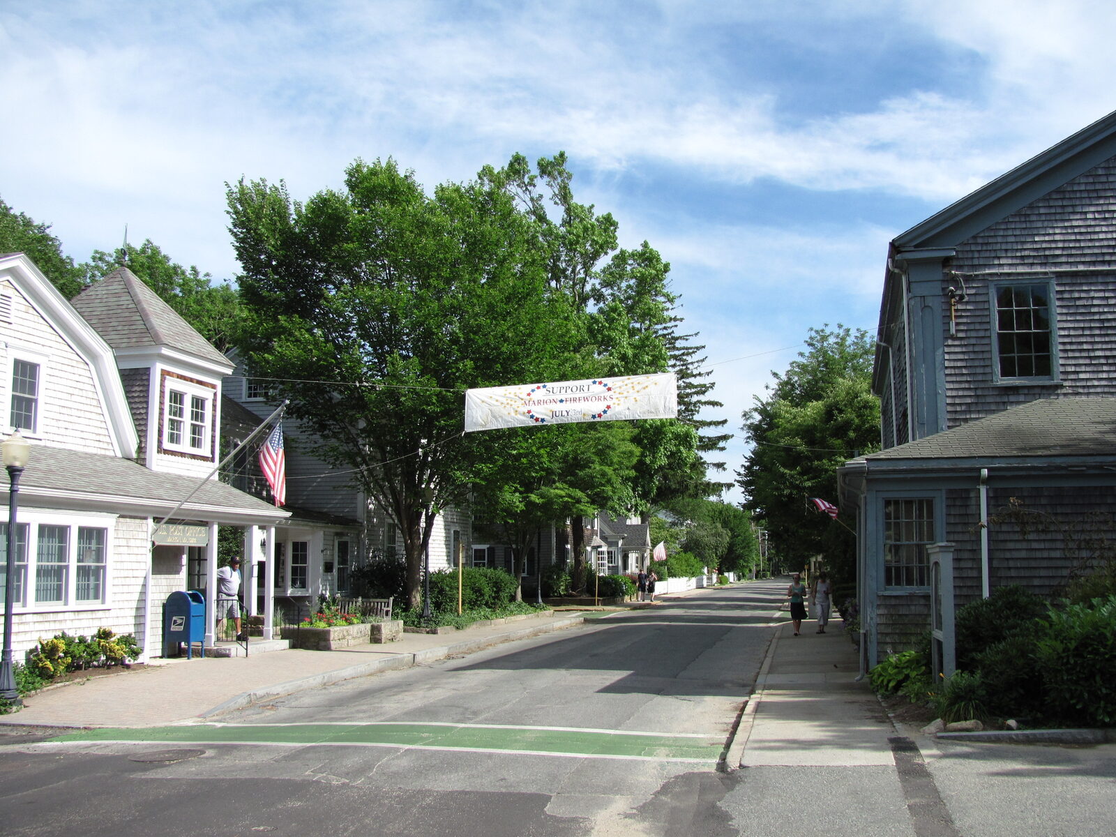 Front Street in Marion village, lined with shingled shops, a sidewalk and street trees