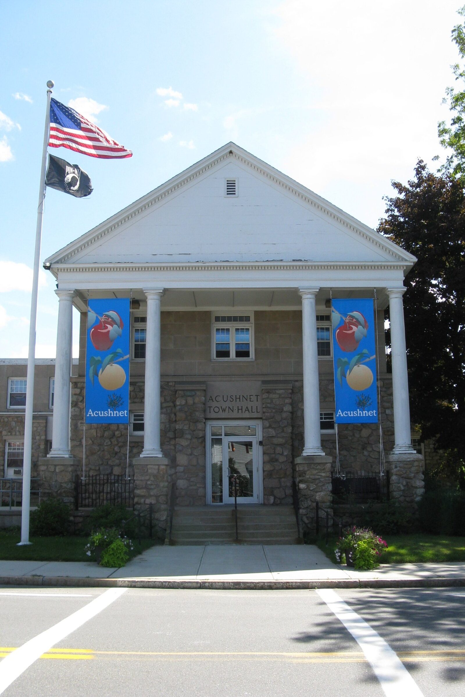 Acushnet Town Hall, a white building with a columned entrance and flags out front