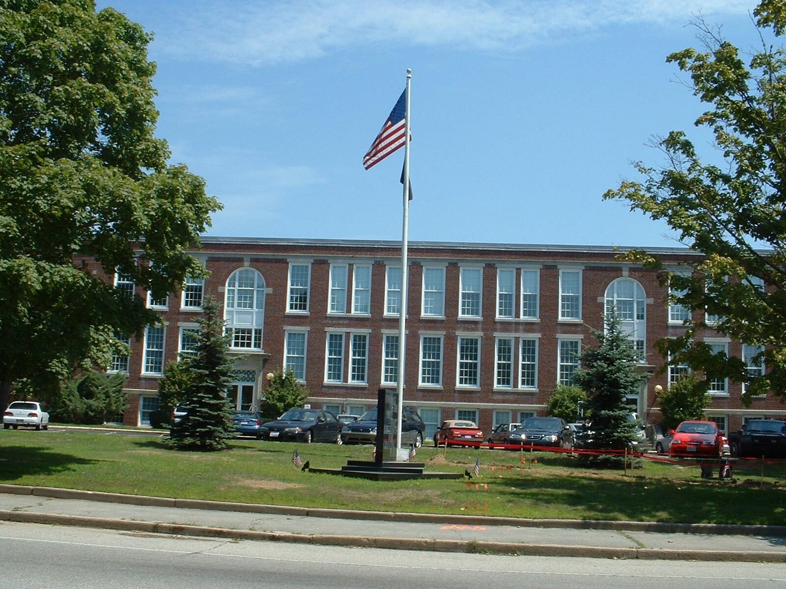 Dartmouth Town Hall, a long three-story brick building behind a lawn and flagpole