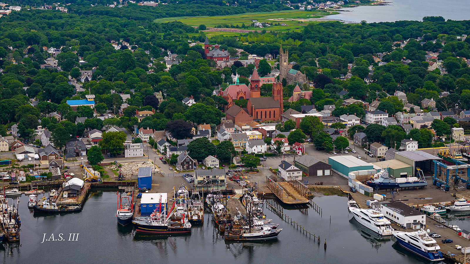 A working harbor with wharves, boats and a church steeple, seen from above